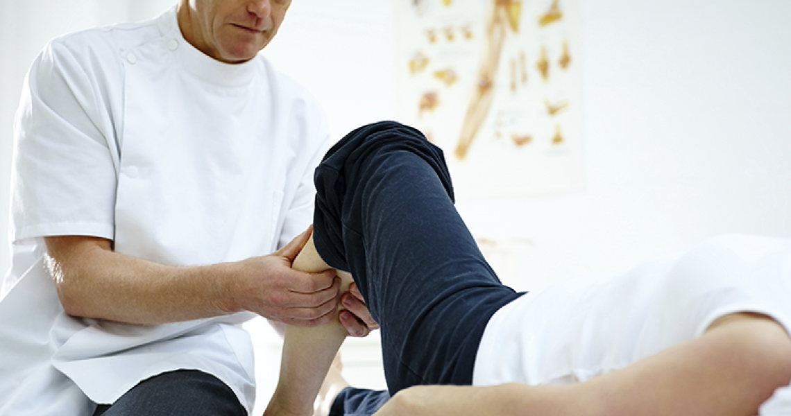 Physical therapist working on a patient's calf in a clinical setting.