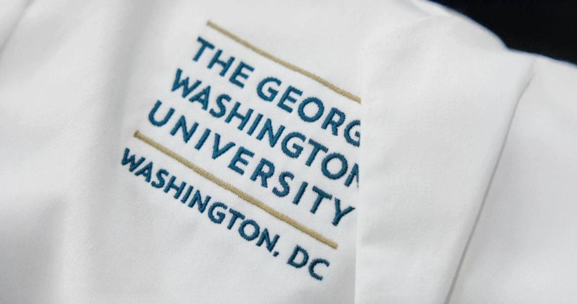 Close up of a doctors white coat with The George Washington University, Washington D.C. embroidered on it.