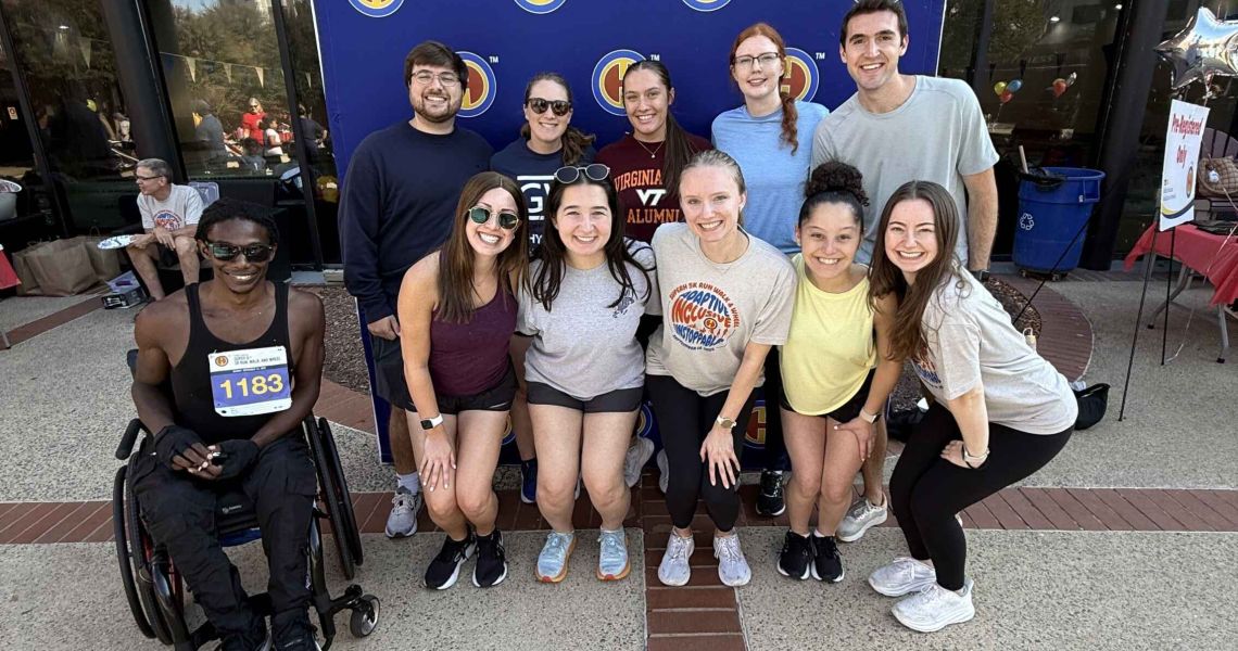 Students pose in front of sign during volunteering at Super H 5K