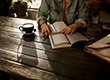 Someone sitting reading a book with a cup of coffee