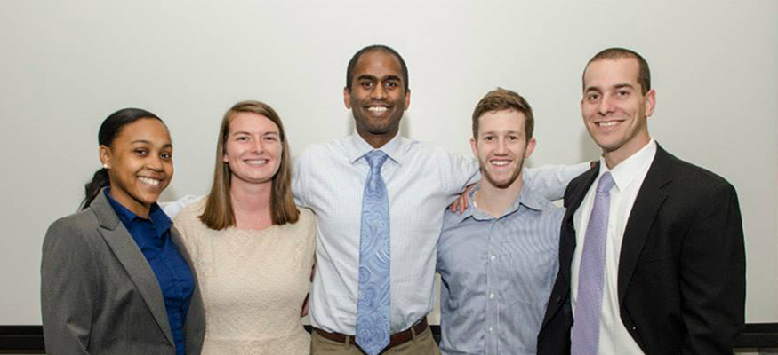 Alumni standing in a row and smiling at the camera