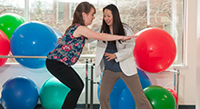 Physical therapist in a clinic working with a patient with exercise balls in view