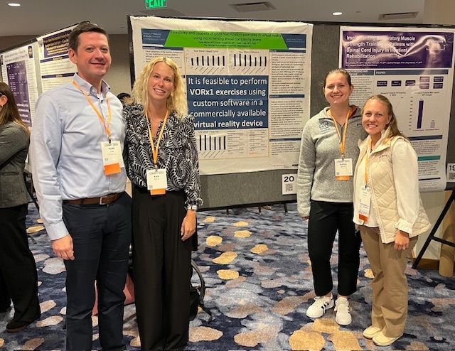 Faculty members Cole and Goodman along with alumna Warren and current student Atkins stand in front of poster at ANPT conference