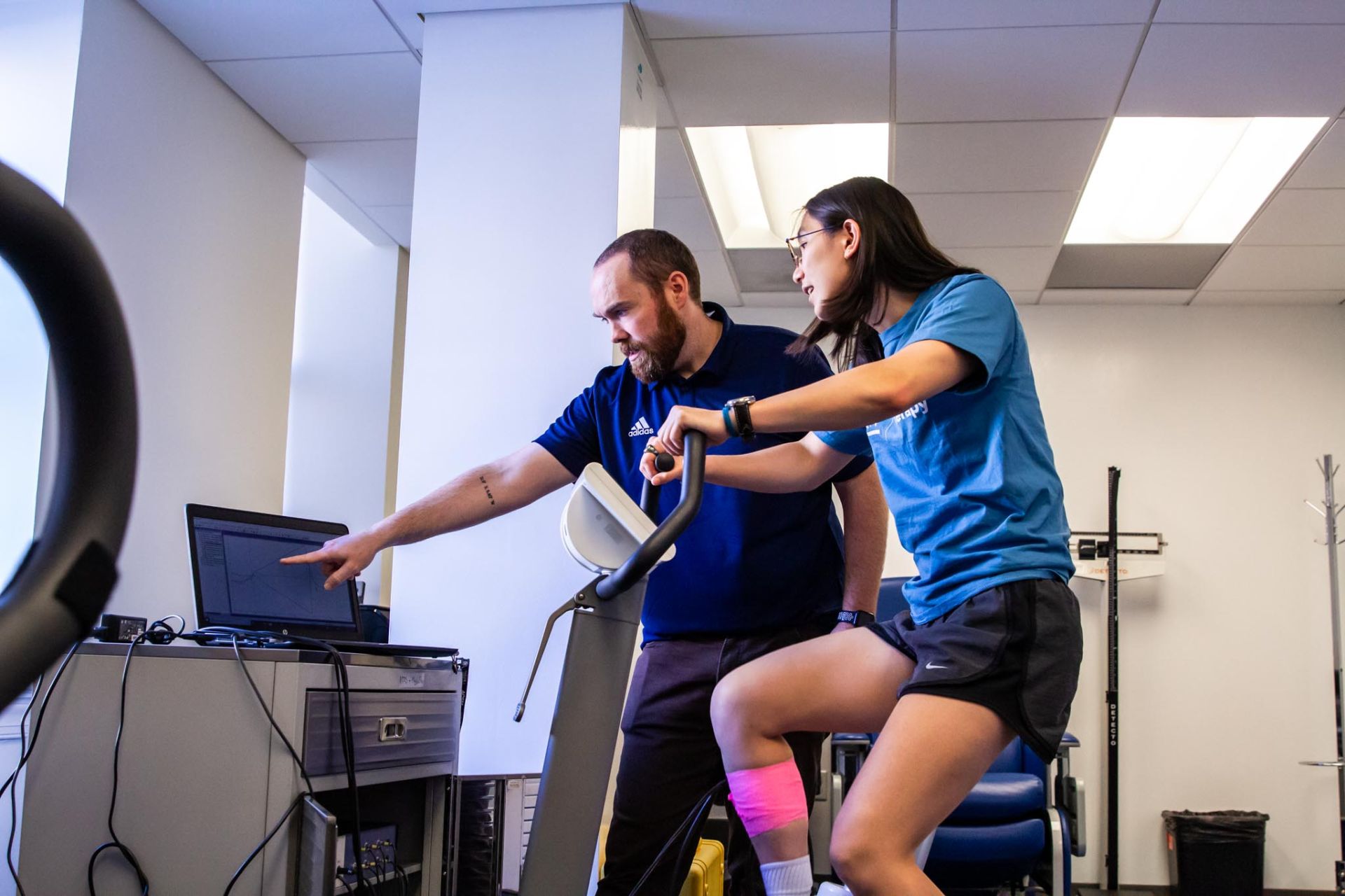Student on stationary bike performing exercise test with faculty member supervising