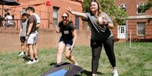 student throwing a hackysack during a game of cornhole