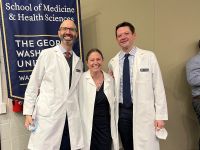 Faculty members Cole, Dring, Wentzell in white coats in front of SMHS banner