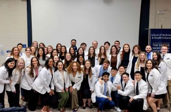 DPT students in white coats pose for group photograph