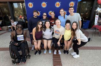 Students pose in front of sign during volunteering at Super H 5K