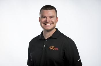 Man in black polo shirt smiling for camera